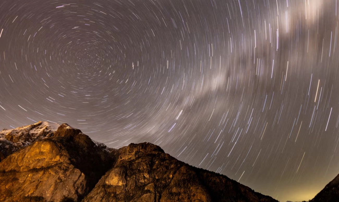 Cielo estrellado con estelas de meteoros sobre montañas durante la lluvia de estrellas Perseidas.